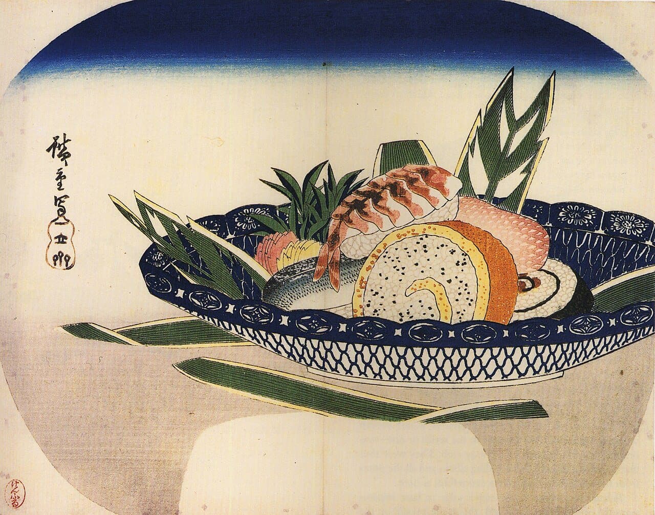染付の鉢に盛られた江戸前のすし。海老、玉子巻き、細巻きなどが笹の葉と一緒に並ぶ団扇絵