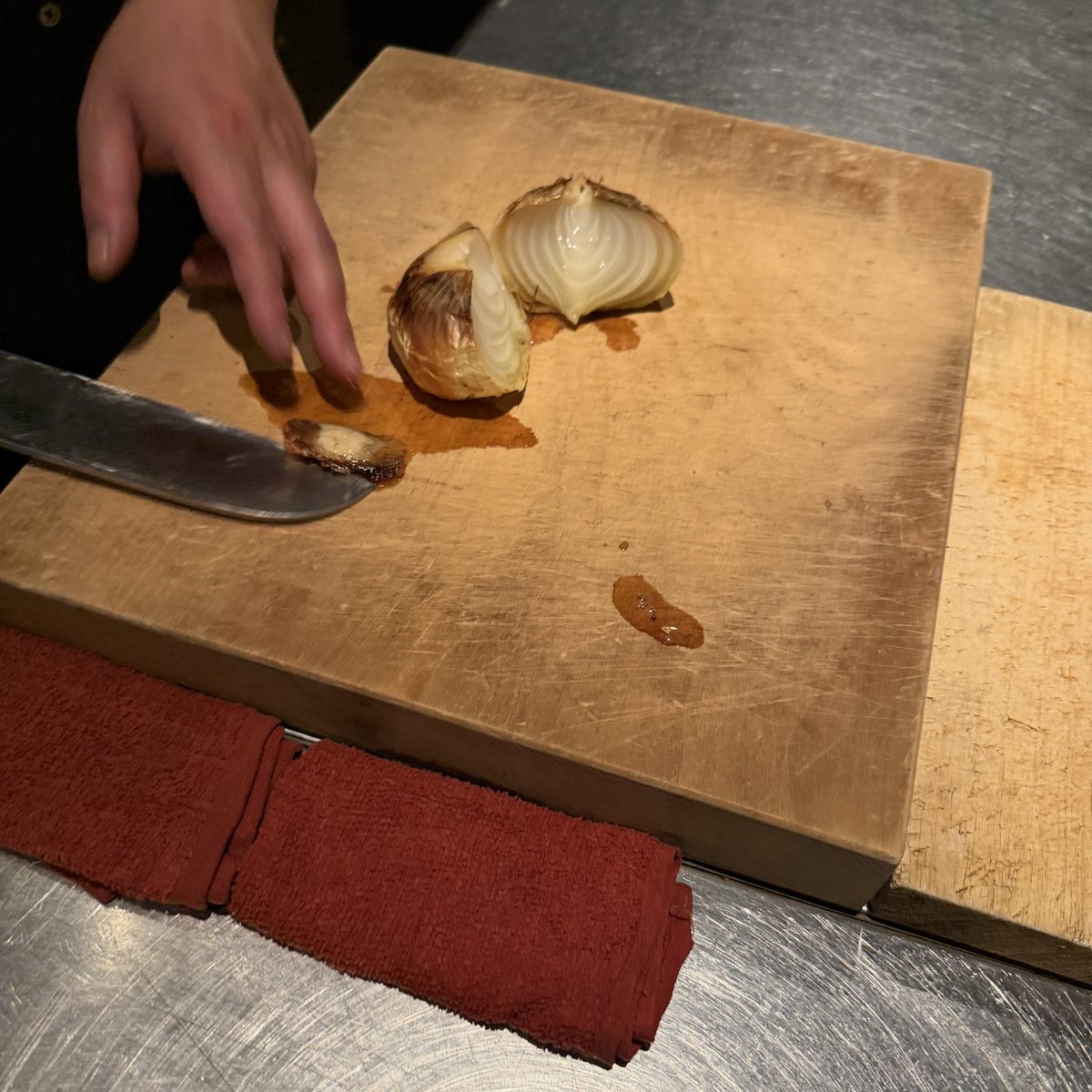The chef's hand and a knife, preparing an onion.