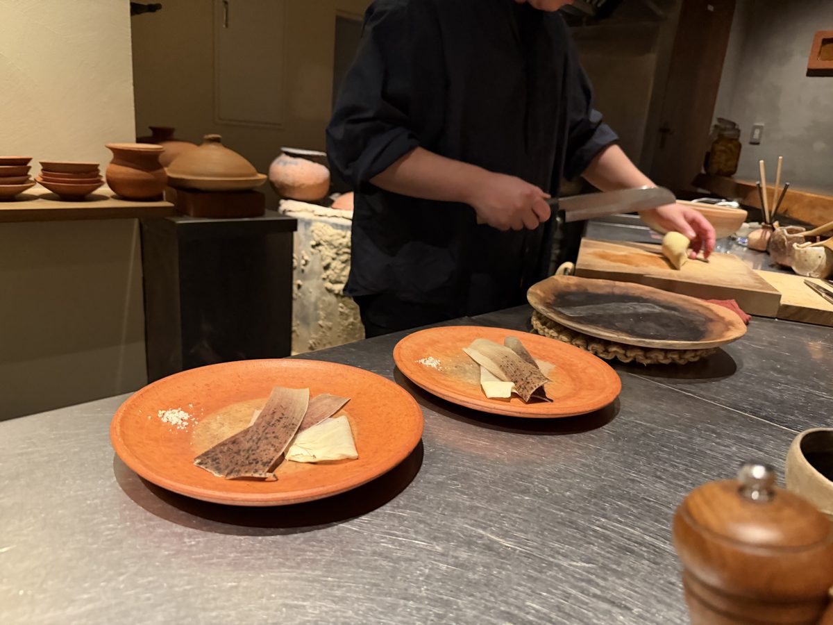 The chef working at the counter, two earthenware plates ready before him.