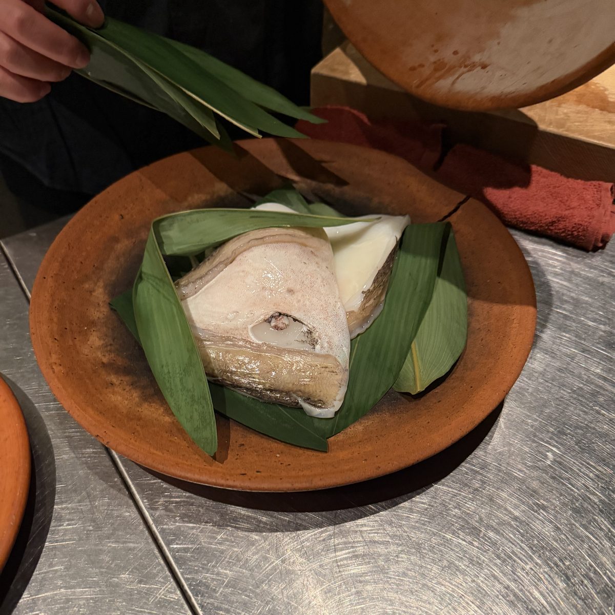 Fish wrapped in bamboo leaves, served on earthenware.