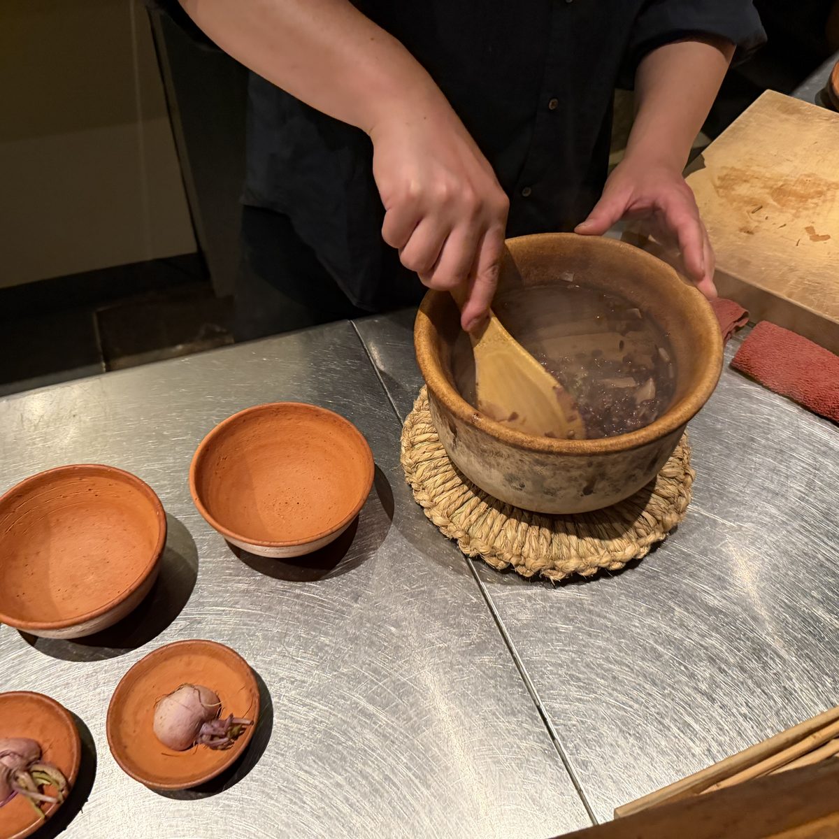 Earthenware bowls arranged on a counter, the chef serving from a clay pot.