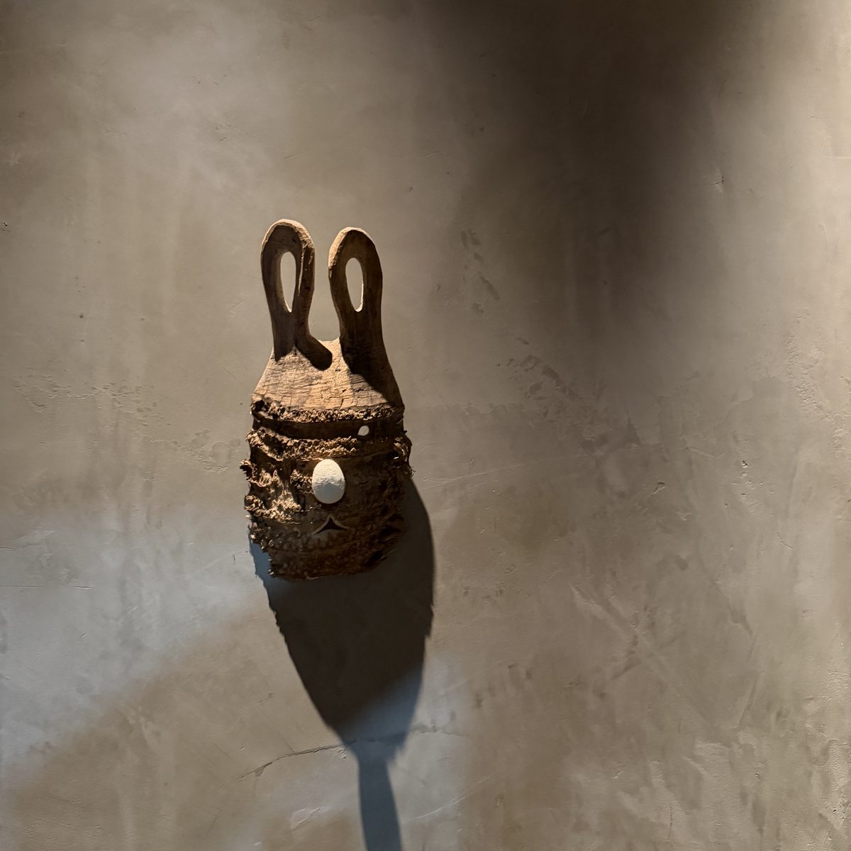 A small carved figure of a hare against a quiet plaster wall.