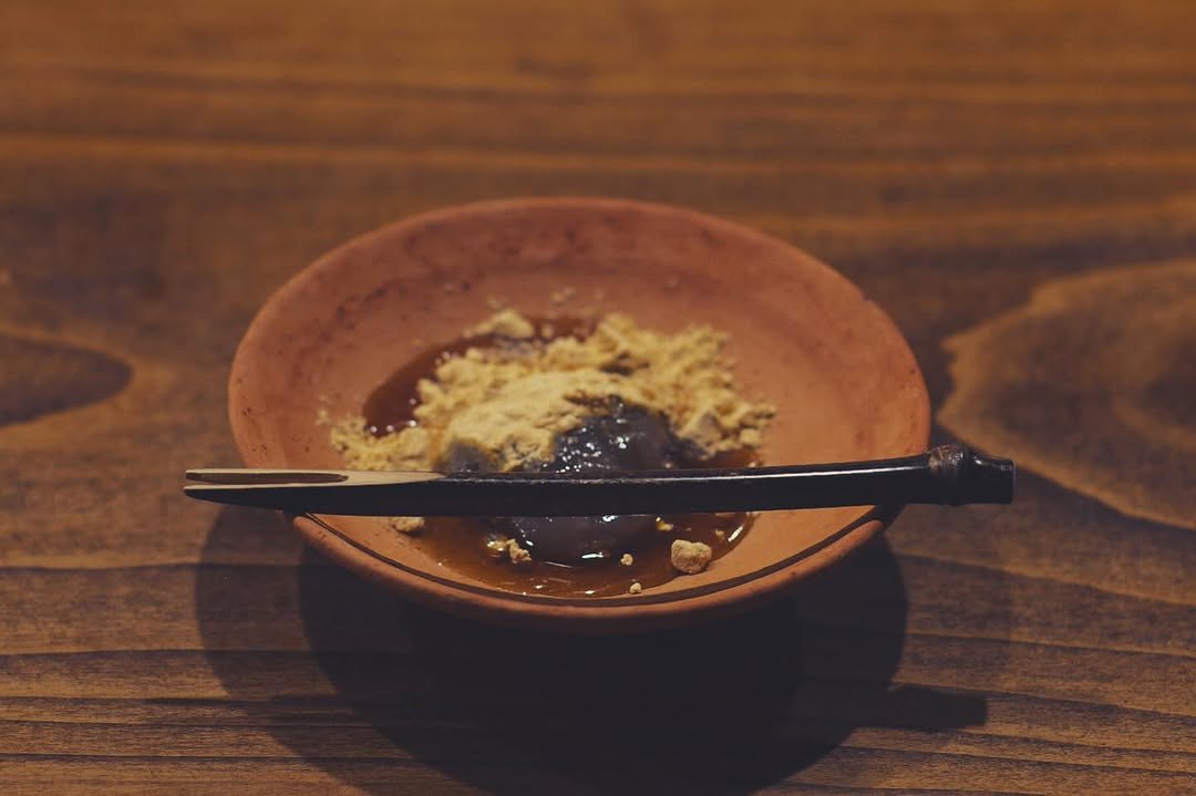 Warabi mochi with black sugar syrup on a clay dish.